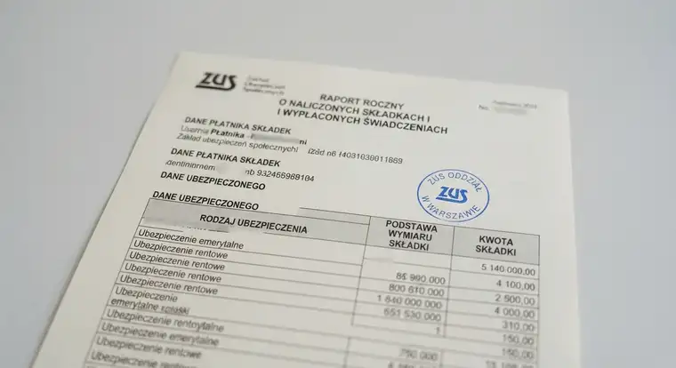 Kobieta trzyma dokument umowy zlecenia i kalkulator, obok leżą okulary, co ilustruje pytanie, czy umowa zlecenie wlicza się do lat pracy do emerytury w 2026 roku